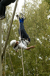 A boy hanging upside down after participating in the Triple Trapeze at our activity centre in Surrey